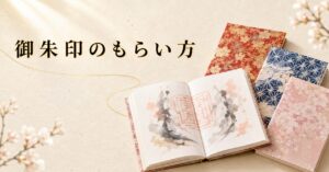 見開きで美しい墨書と朱印が記された御朱印帳が中央にあり、周囲に閉じた御朱印帳が静かに並ぶ構図。生成り washi 背景にタイトル「御朱印のもらい方」を配したアイキャッチ画像