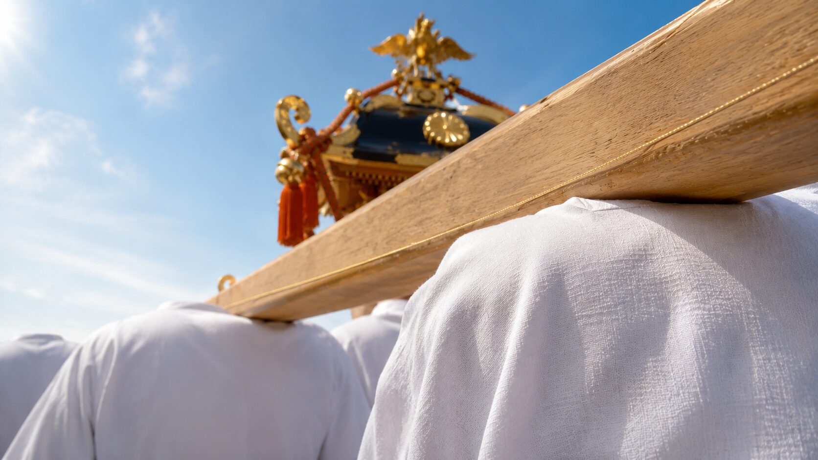 神田祭の神輿宮入の場面、自分視点で神輿の担ぎ棒に肩を入れる瞬間の painterly な情景。右手前に自分の右肩(白い半被=祭礼半纏の襟元と上腕が見える)が大きく入り、画面中央上部に金色の装飾を持つ神輿の屋根と房飾りが見える。背景には夏の青空と他の担ぎ手の半被の白い背中(顔不可視)が薄く見える。神輿渡御の熱気を伝える担ぎ手目線の構図