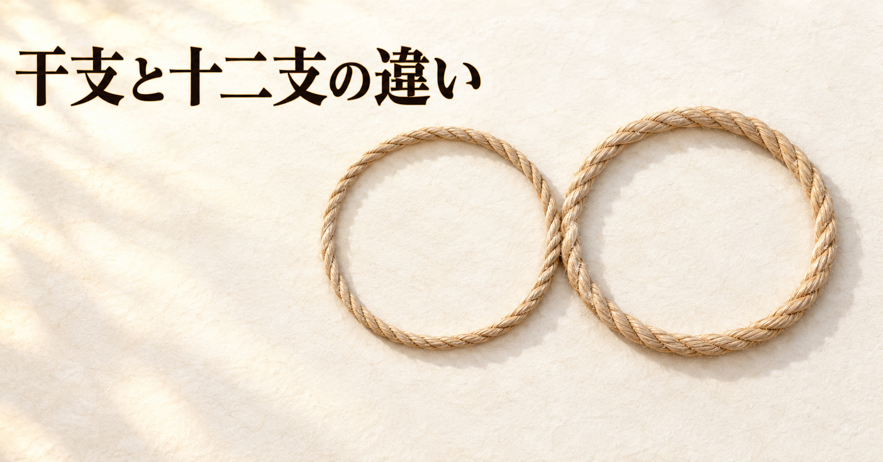 ivory washi 背景の painterly なアイキャッチ画像。画面右側に生成り色の無地の縄が2本置かれ、それぞれがゆるやかな輪をつくって1か所だけで重なり合っている。太さがわずかに違う2本はどちらも同じ明るさで、朝の斜光が縄の縁に薄い影を落とす。左上に「干支と十二支の違い」の横書きタイトル。